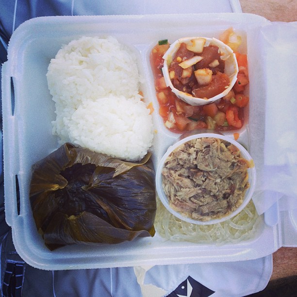 Traditional Hawaiian plate lunch with lau-lau, kalua pork, lomi-lomi salmon, rice, and noodles.