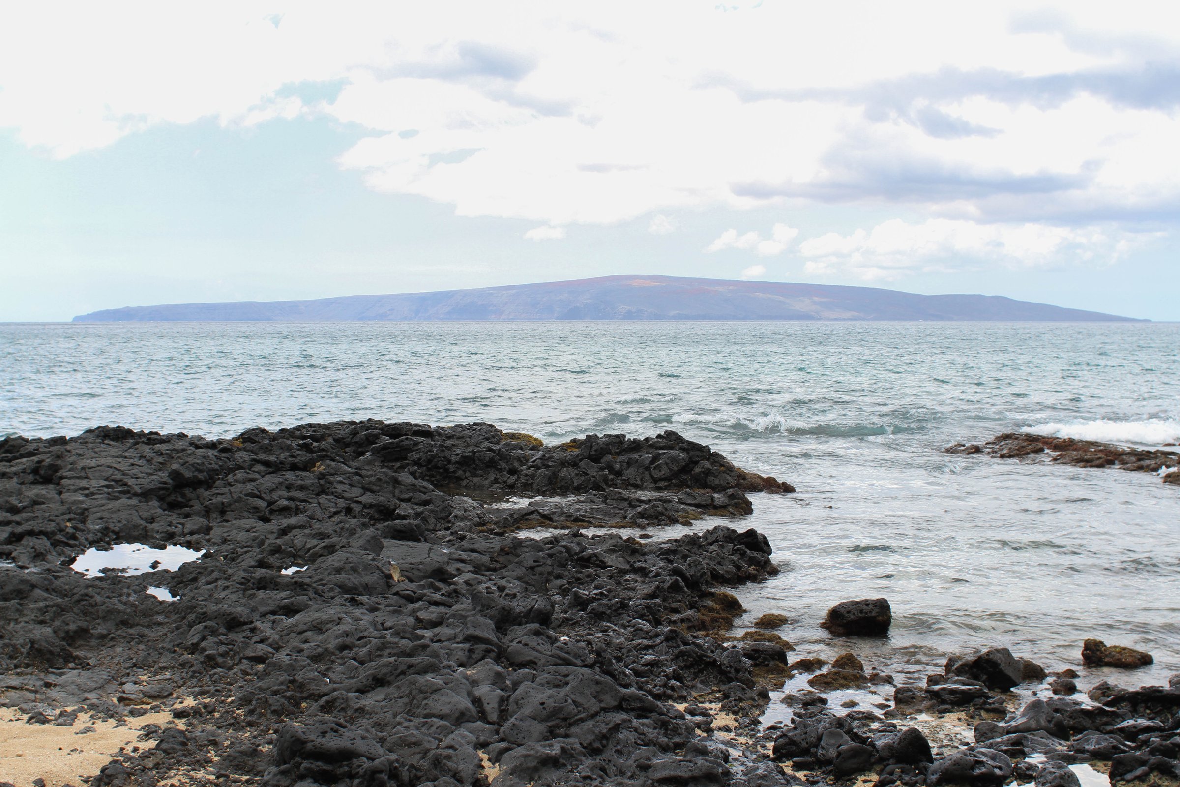 The low, dry shield-volcano island of Kahoʻolawe on the horizon, seen across the water from Mākena on Maui.
